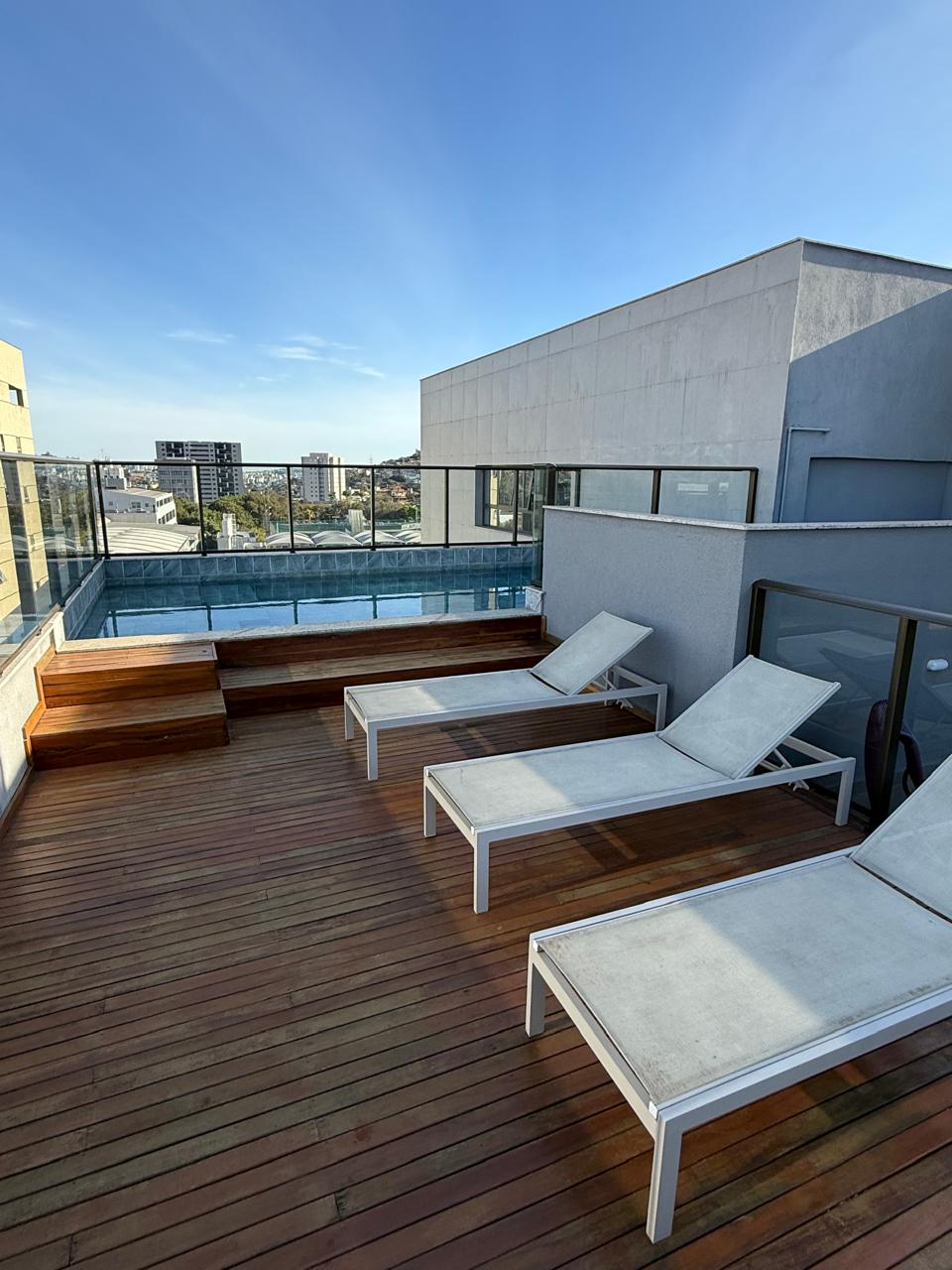 Piscina na cobertura com deck de madeira e espreguiçadeiras