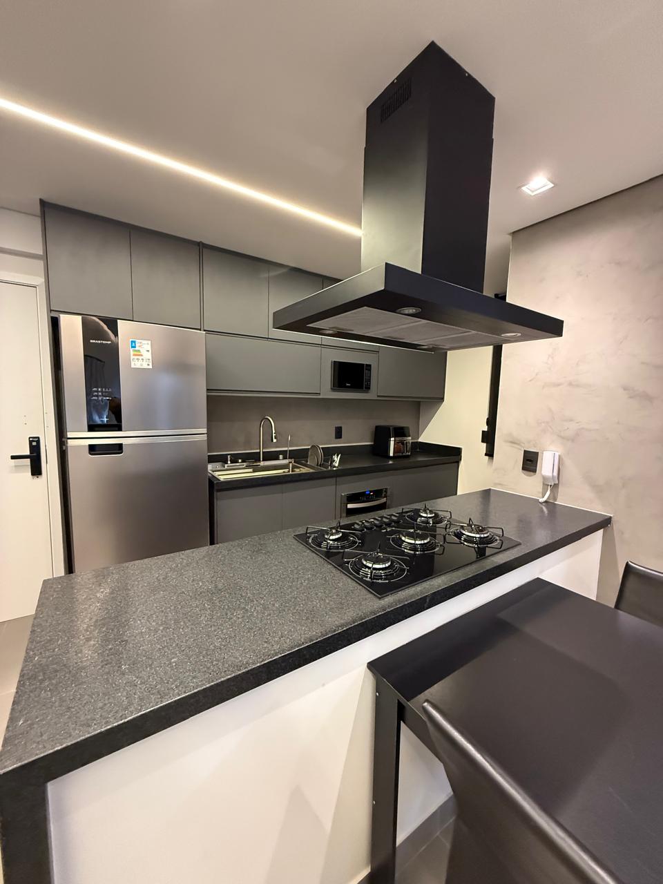 Cozinha gourmet com cooktop, coifa e bancada em granito